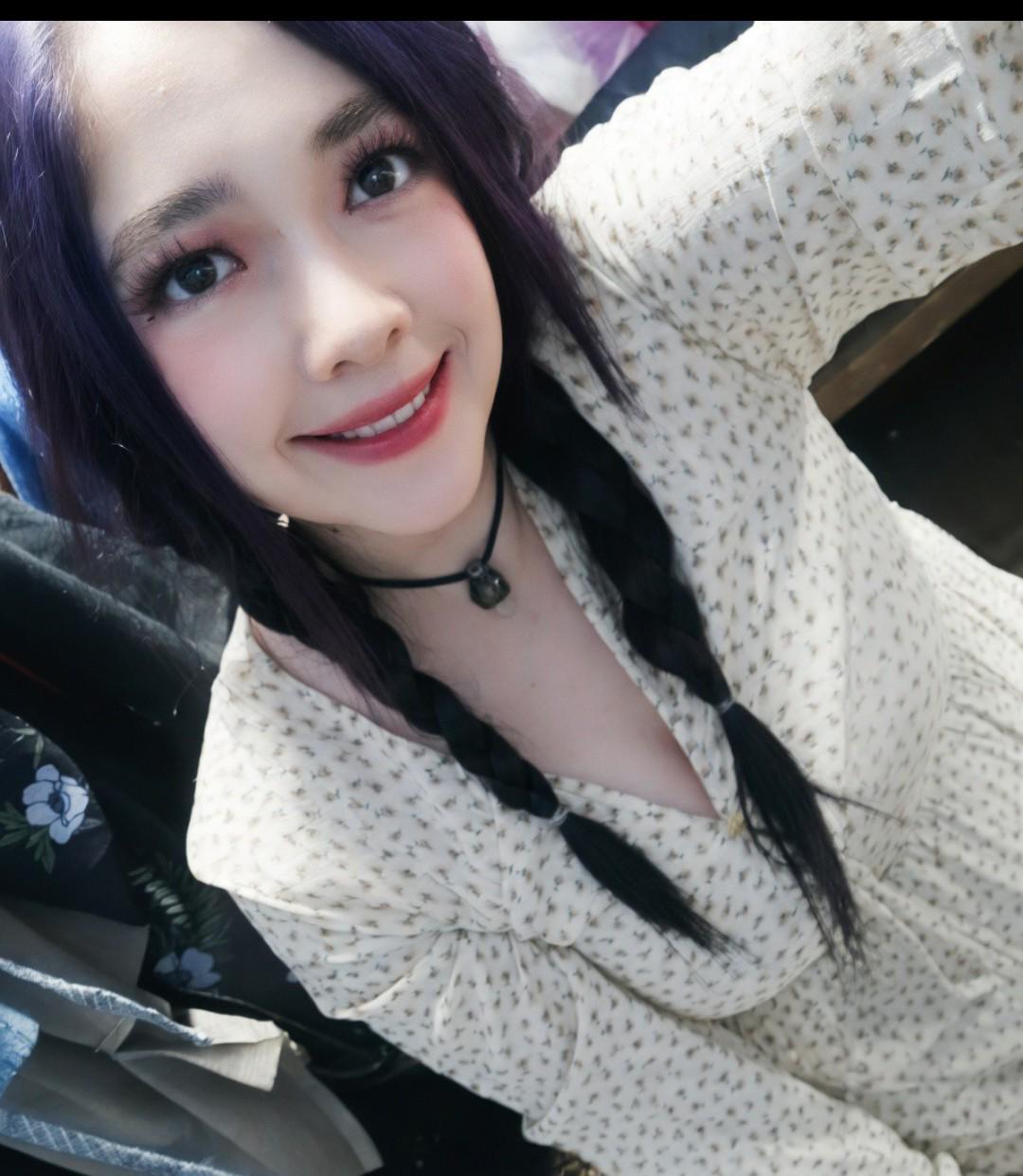 Ella, sonriendo, con el cabello violeta y una trenza.